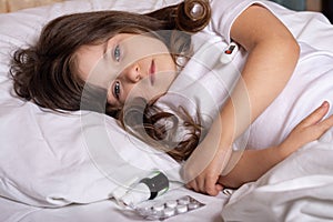 Sick kid with thermometer laying in bed and taking temperature. Checking temperature using thermometer.