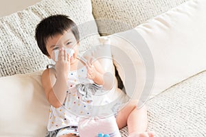 Sick little Asian girl wiping or cleaning nose with tissue