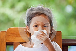 Sick little asian girl wiping or cleaning nose with tissue