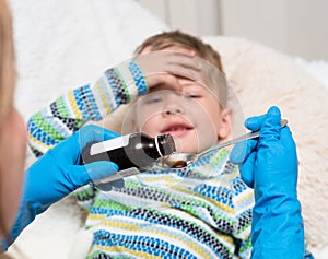 Sick little boy awaits her medication pouring in a spoon