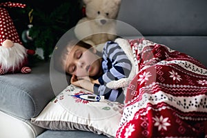 Sick little child, boy, with high fever sleeping on the couch at