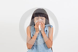 Sick little girl blowing her nose isolated on white