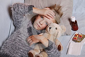 Sick little girl lying in the bed with her toy. Child winter flu allergy health care concept