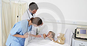 Sick little girl lying in bed talking to nurse and doctor