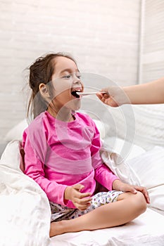 Sick little girl lying in bed with thermometer