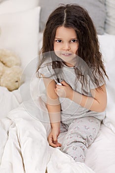 Sick little girl lying in bed with thermometer