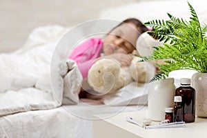 Sick little girl lying in bed with thermometer