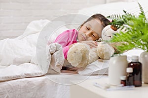 Sick little girl lying in bed with thermometer