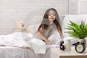 Sick little girl lying in bed with thermometer