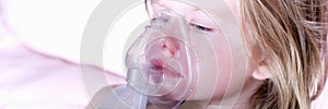 Sick little girl in medical oxygen mask using nebulizer