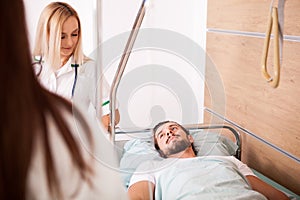Sick male Patient in hospital room next to nurses