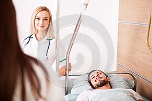 Sick male Patient in hospital room next to nurses