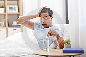 Sick man in bed with medicine and glass of water