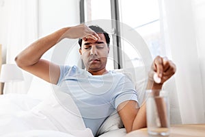 Sick man in bed with medicine and glass of water