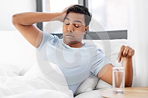 Sick man in bed with medicine and glass of water