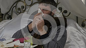 A sick man blowing his nose as having a runny nose during a cold or influenza. slow motion