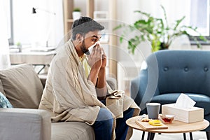 Sick man blowing nose in paper tissue at home