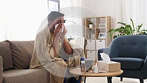 Sick man blowing nose in paper tissue at home