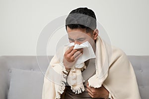 Sick man  blowing nose and sneeze into tissue. Male have flu, virus or allergy respiratory