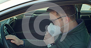 Sick man in the car coughs sneeze wearing Protective Face Mask COVID-19 coronavirus infection pandemic disease virus.