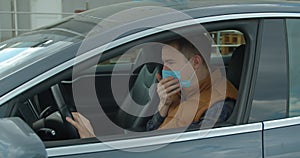 Sick man in the car coughs sneeze wearing Protective Face Mask COVID-19 coronavirus infection pandemic disease virus.