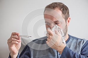 Sick man checks the body temperature with a mercury thermometer. Theme of viral diseases, flu, colds