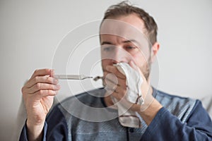 Sick man checks the body temperature with a mercury thermometer. Theme of viral diseases, flu, colds