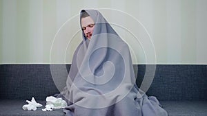 Sick man covered with blanket is yawns