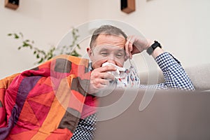 Sick man with handkerchief by his nose staying at home.