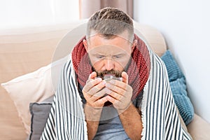 Sick man having fever, drinking hot healing tea.
