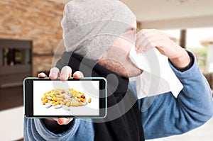 Sick man holding cellphone and blowing nose