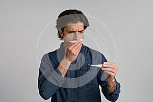 Sick Man Holding Thermometer, Checking His High Temperature Over Light Background