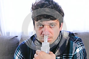 Sick man inhaling through inhaler nozzle for nose. Close-up face, front view. Use nebulizer and inhaler for the