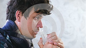 Sick man inhaling through inhaler nozzle for nose. Close-up face, side view. Use nebulizer and inhaler for the treatment