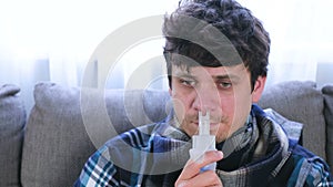 Sick man inhaling through inhaler nozzle for nose sitting on the sofa. Close-up face, front view. Use nebulizer and