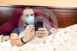 Sick man laying in bed using smarthphone