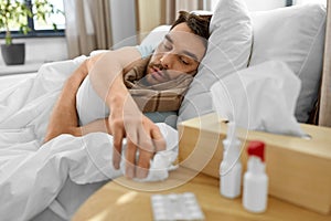 sick man lying in bed and taking tissue from table