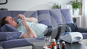 Sick man lying on the couch he`s blurred. selective focus on medicines