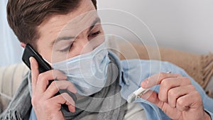 Sick man in mask with thermometer calling doctor