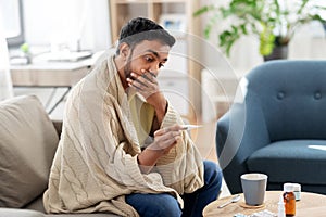 Sick man measuring temperature by thermometer