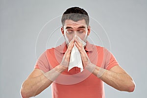 Sick man with paper napkin blowing nose