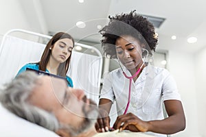 Sick man patient with African American female doctor listens his chest with stethoscope in hospital emergency room. Doctor and