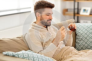 Sick man pouring medication from bottle to spoon