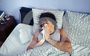 Sick man sneezing and covering nose with tissue