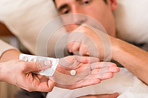 Sick man taking medication offered by a nurse