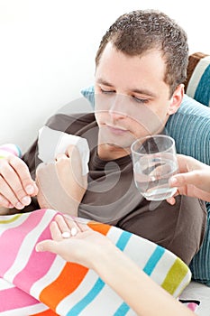 Sick man taking medicine on the sofa