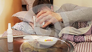 Sick man taking pill while lying on bed