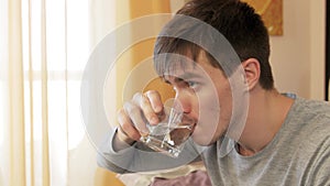 Sick man taking pill while sitting in living room