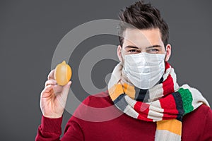 sick man in warm scarf and medical mask holding lemon,