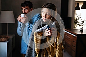 Sick man and woman wrapped in blankets suffering from cold or flu